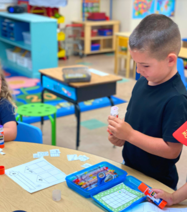 Child holding a glue stick in a classroom