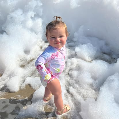 Child standing in sea foam