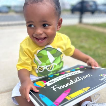Child holding a sign that says "My First Day of Foundations"