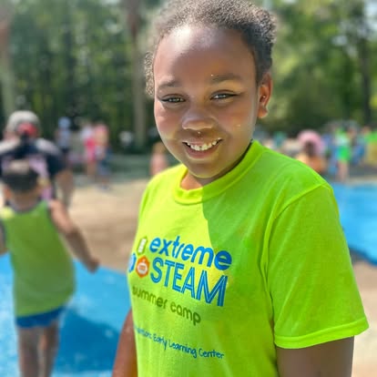 Child in a neon green shirt with "extreme STEAM summer camp" text