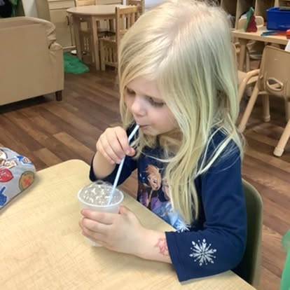 Child drinking from a cup with a straw