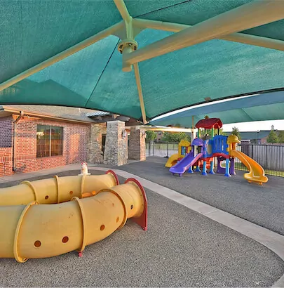 Playground with yellow tunnels and colorful play structure under a shade canopy