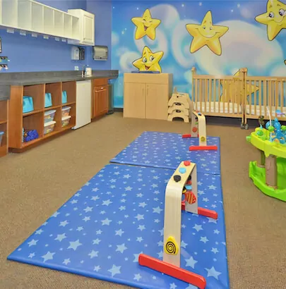 Nursery room with cribs, play mats, and star-themed wall decor