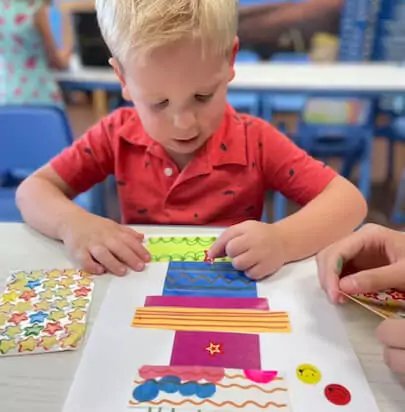 Child creating art with colorful paper and stickers