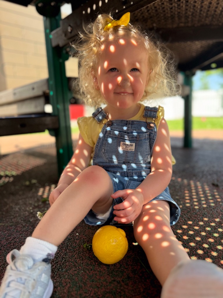 Child sitting on ground with a lemon