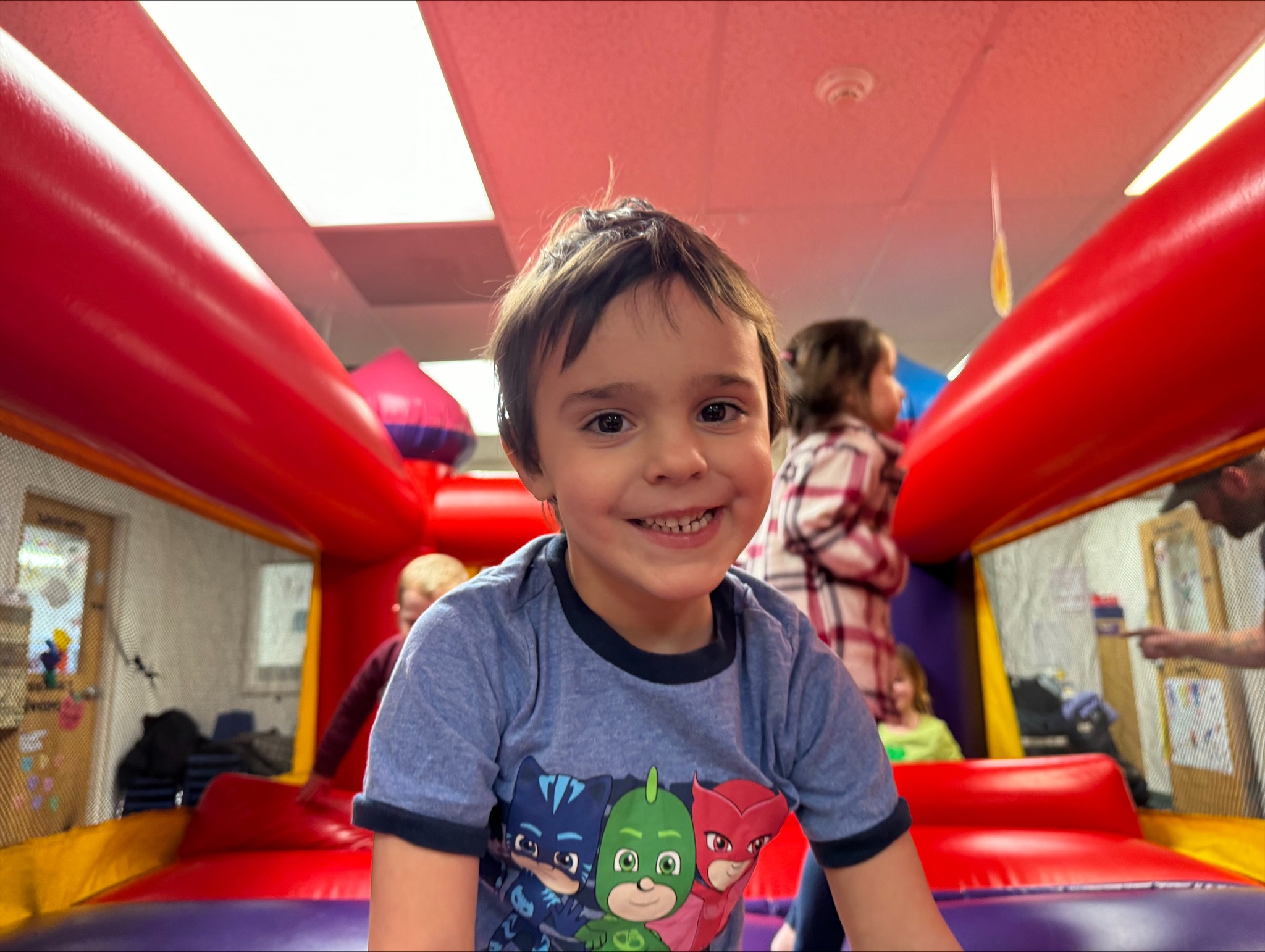 Child in a blue shirt smiling in an inflatable play structure