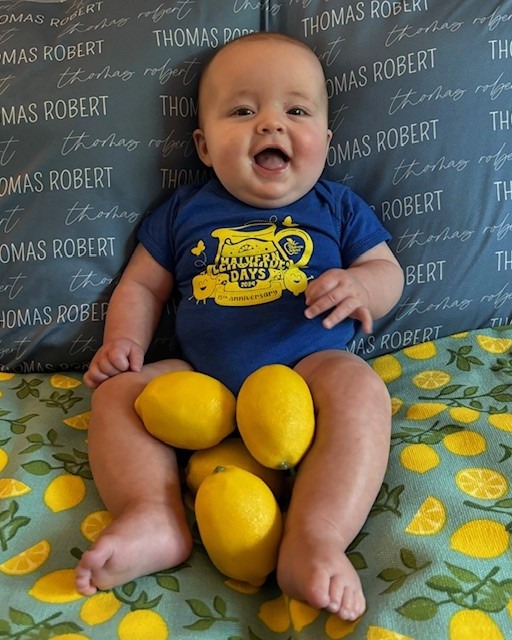Child sitting with lemons on a lemon-patterned blanket