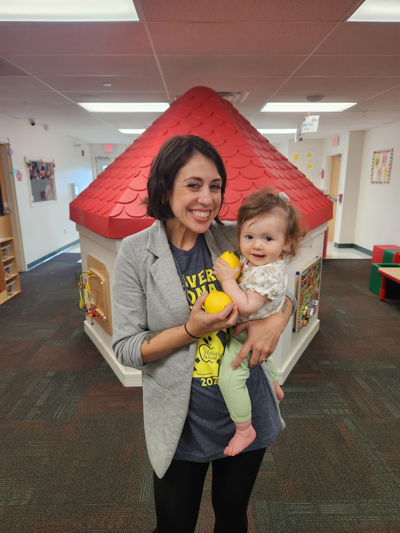 Person holding a child in a room with a playhouse