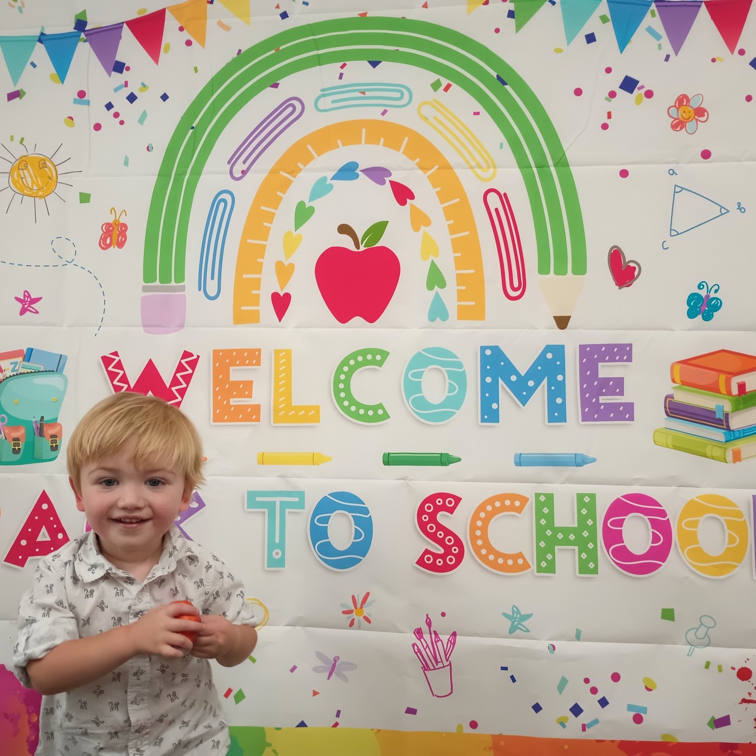 Child standing in front of a "Welcome to School" sign
