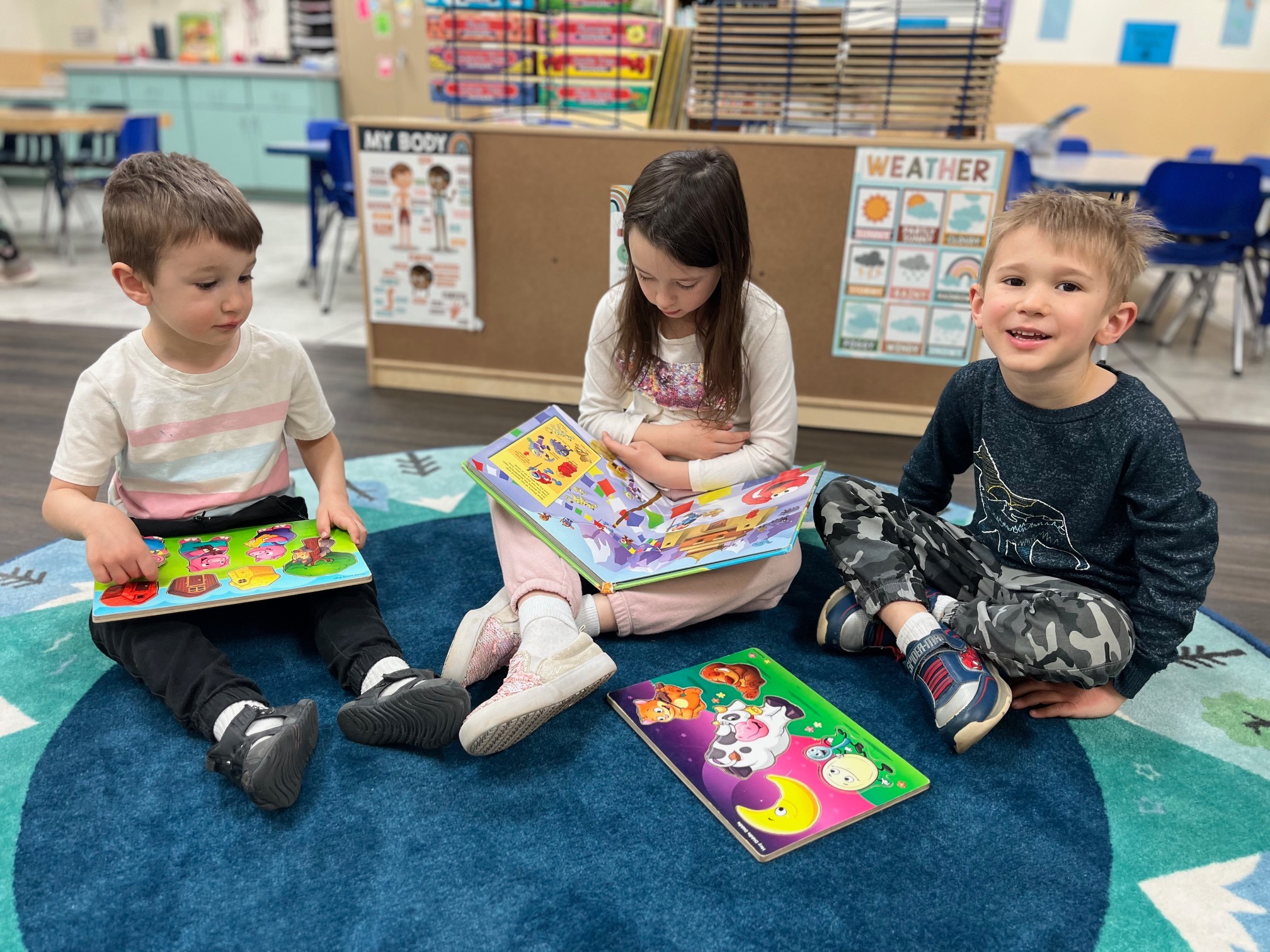 Three children sitting on a rug with puzzles and books