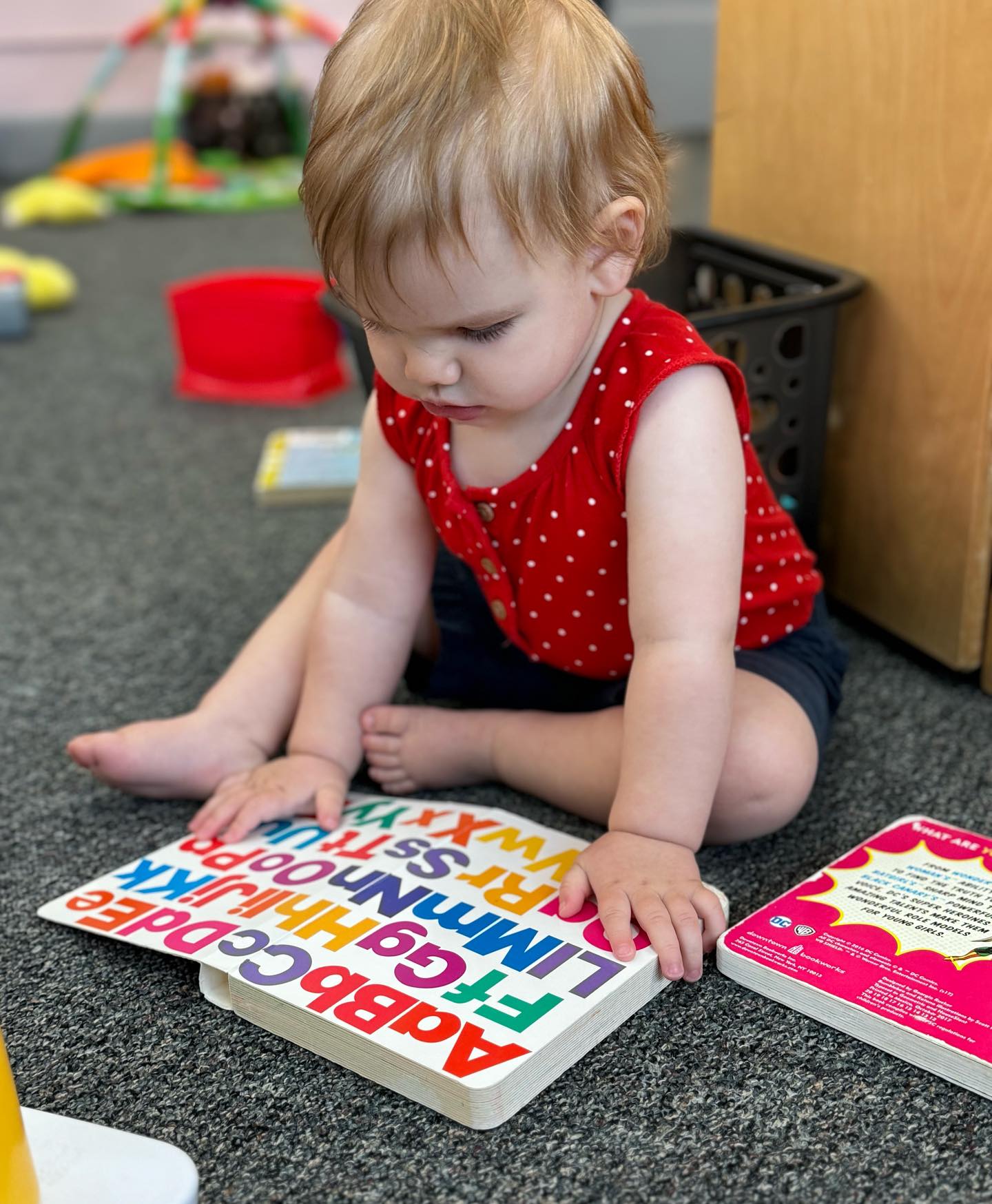 Child sitting on floor looking at an alphabet book