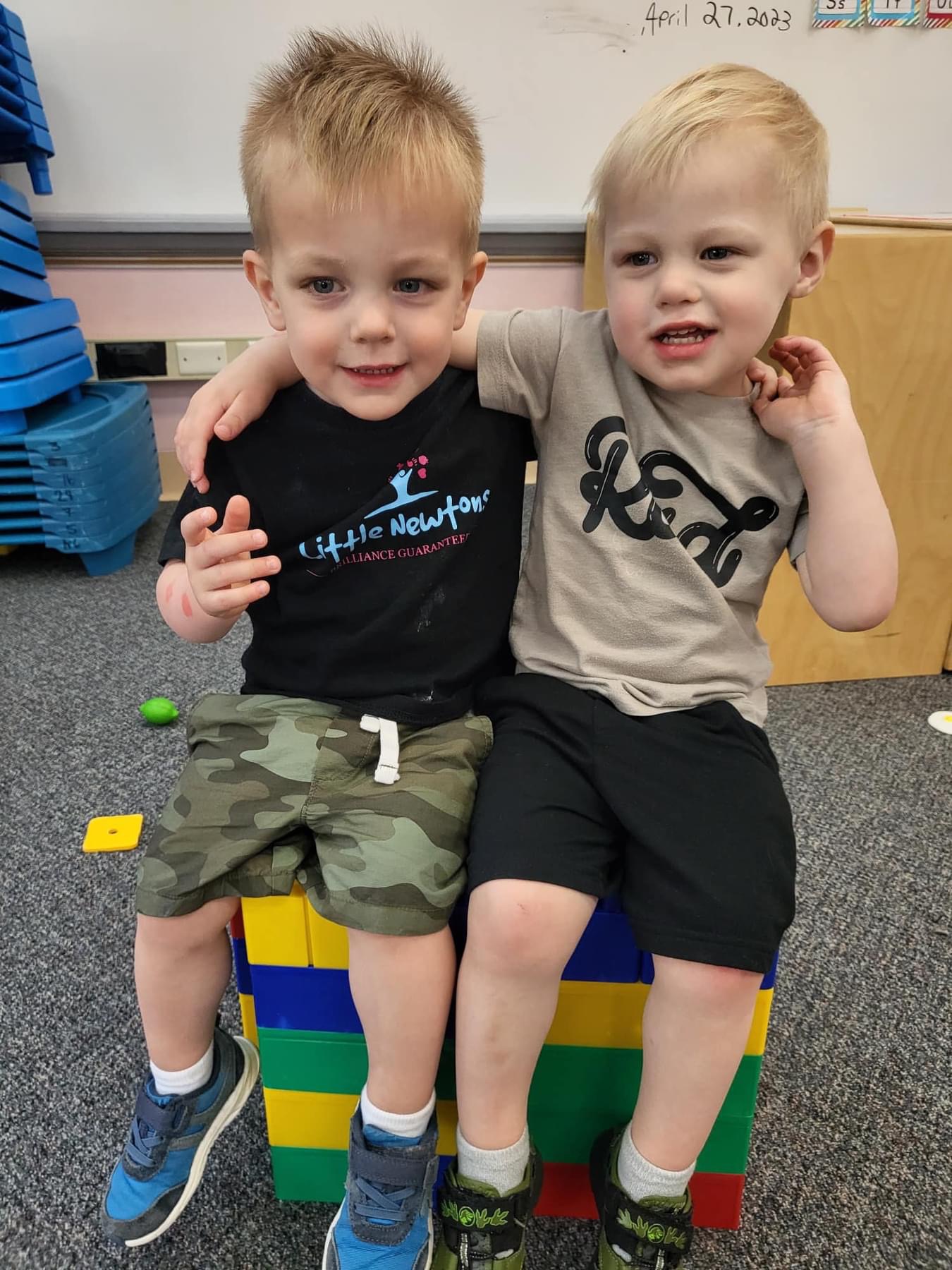 Two children sitting together, one with arm around the other