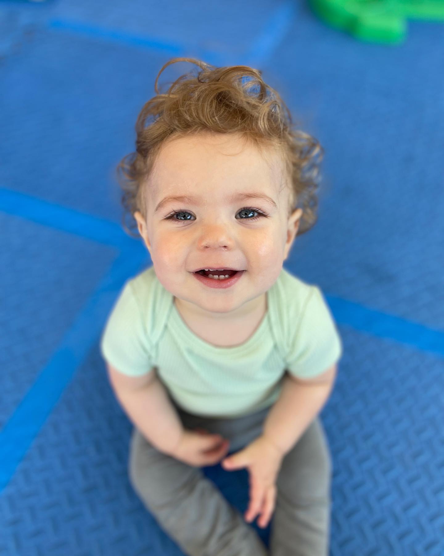 Child sitting on a blue mat looking up