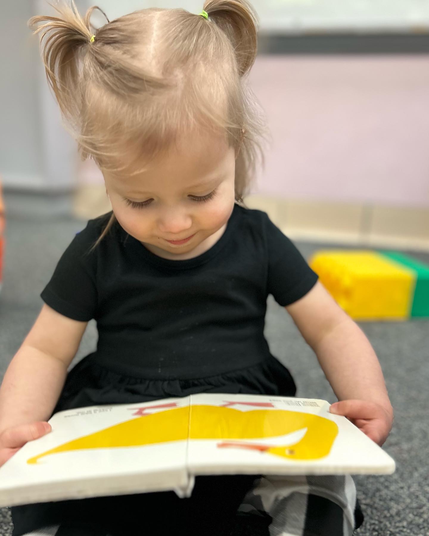 Child with pigtails looking down at an open book