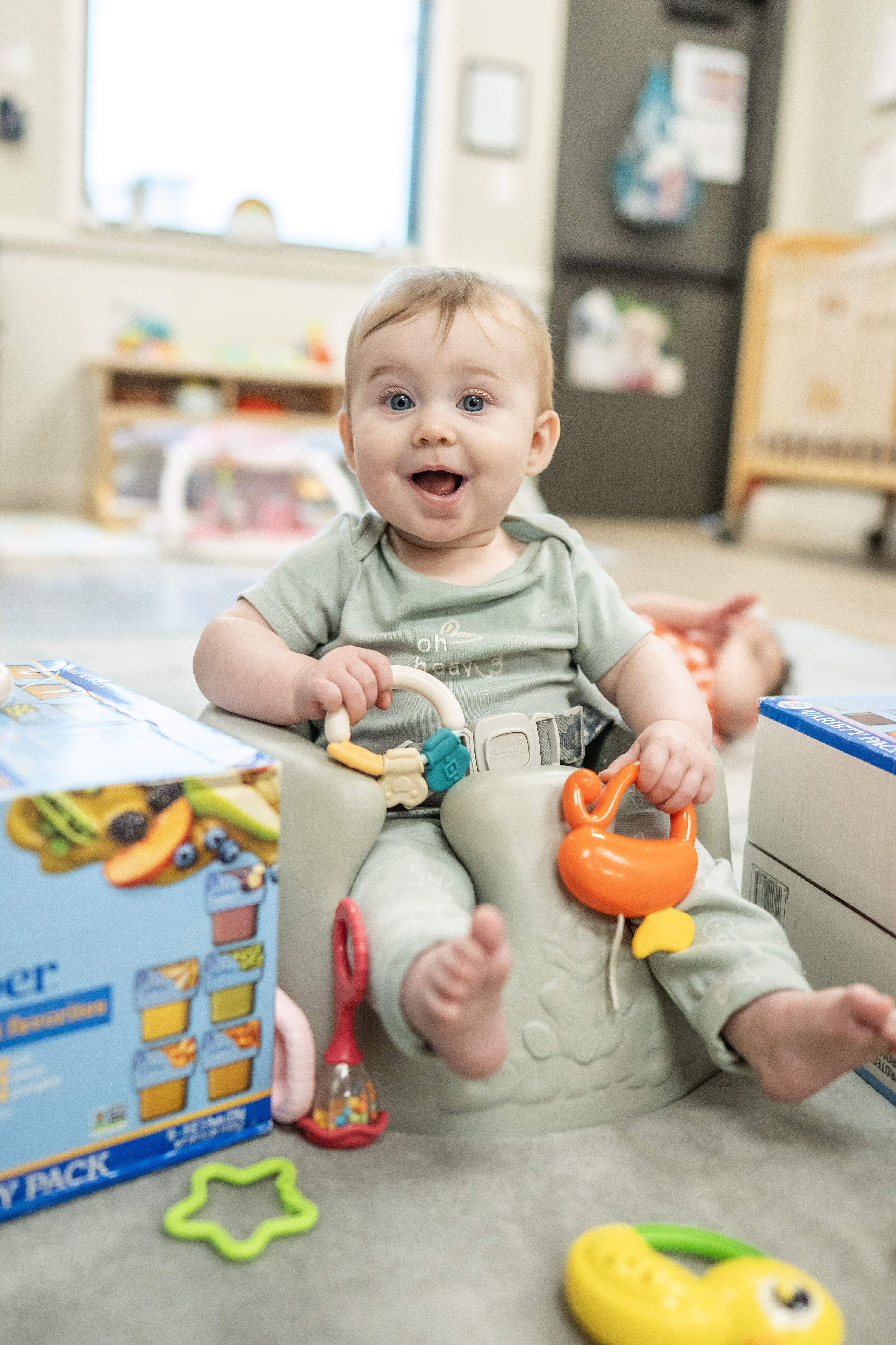 Child sitting in a floor seat with toys in a room