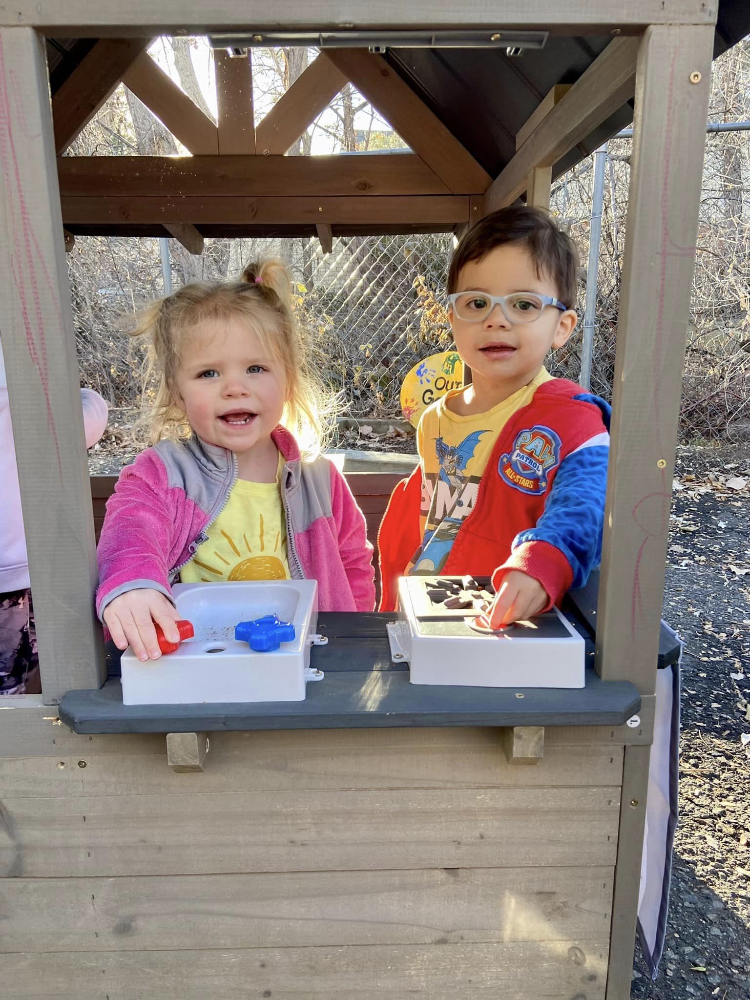 Two children playing in a wooden playhouse