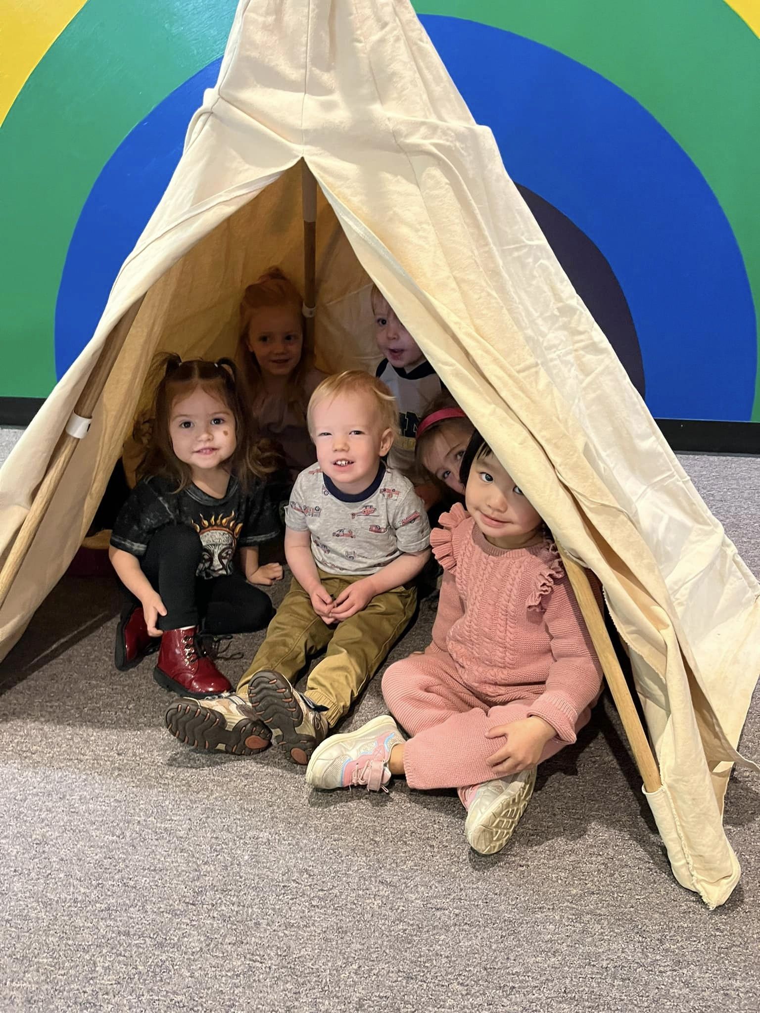 Several children sitting inside a teepee