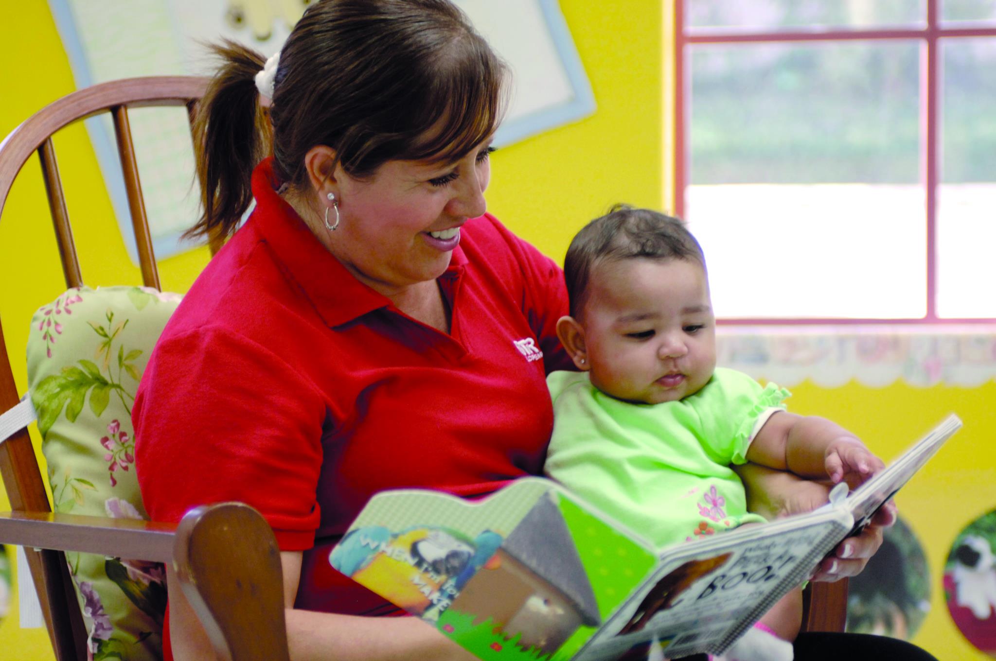 Person holding a child and reading a book together