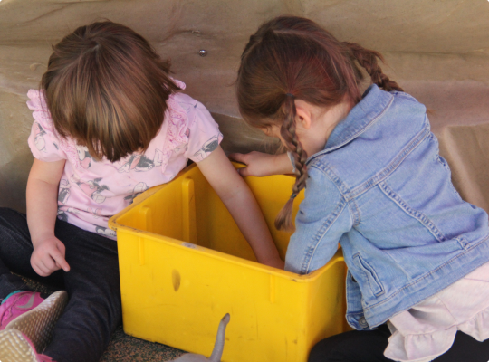 Two children playing with a yellow bin