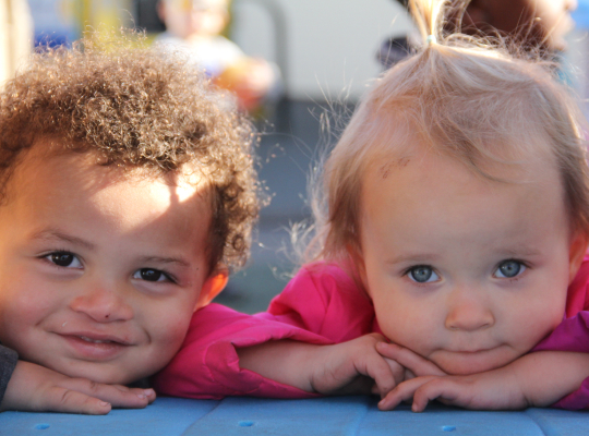 Two children resting their chins on a surface