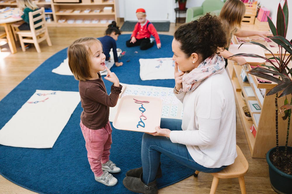 Adult and child interacting in a classroom, child pointing at adult