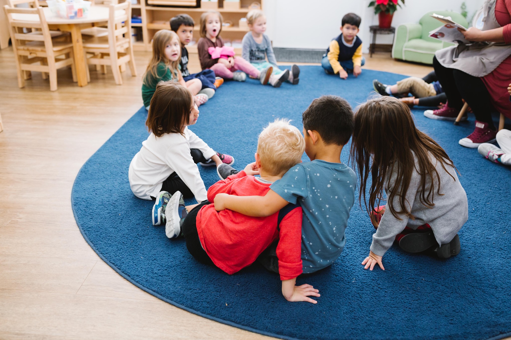 Children sitting on a blue rug in a classroom