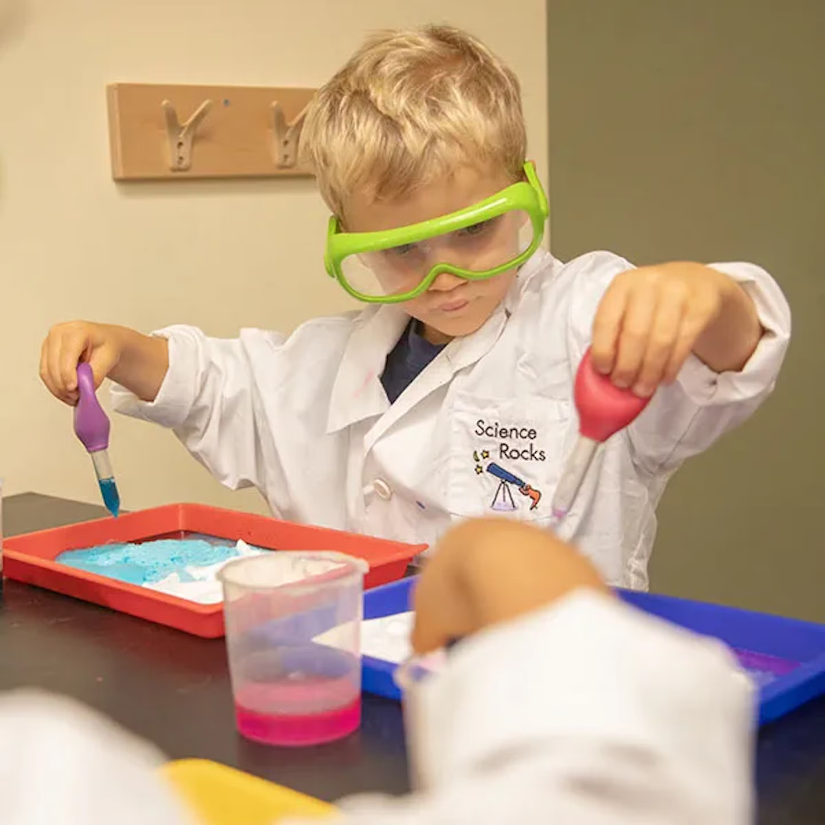 Child in lab coat and safety goggles doing a science experiment