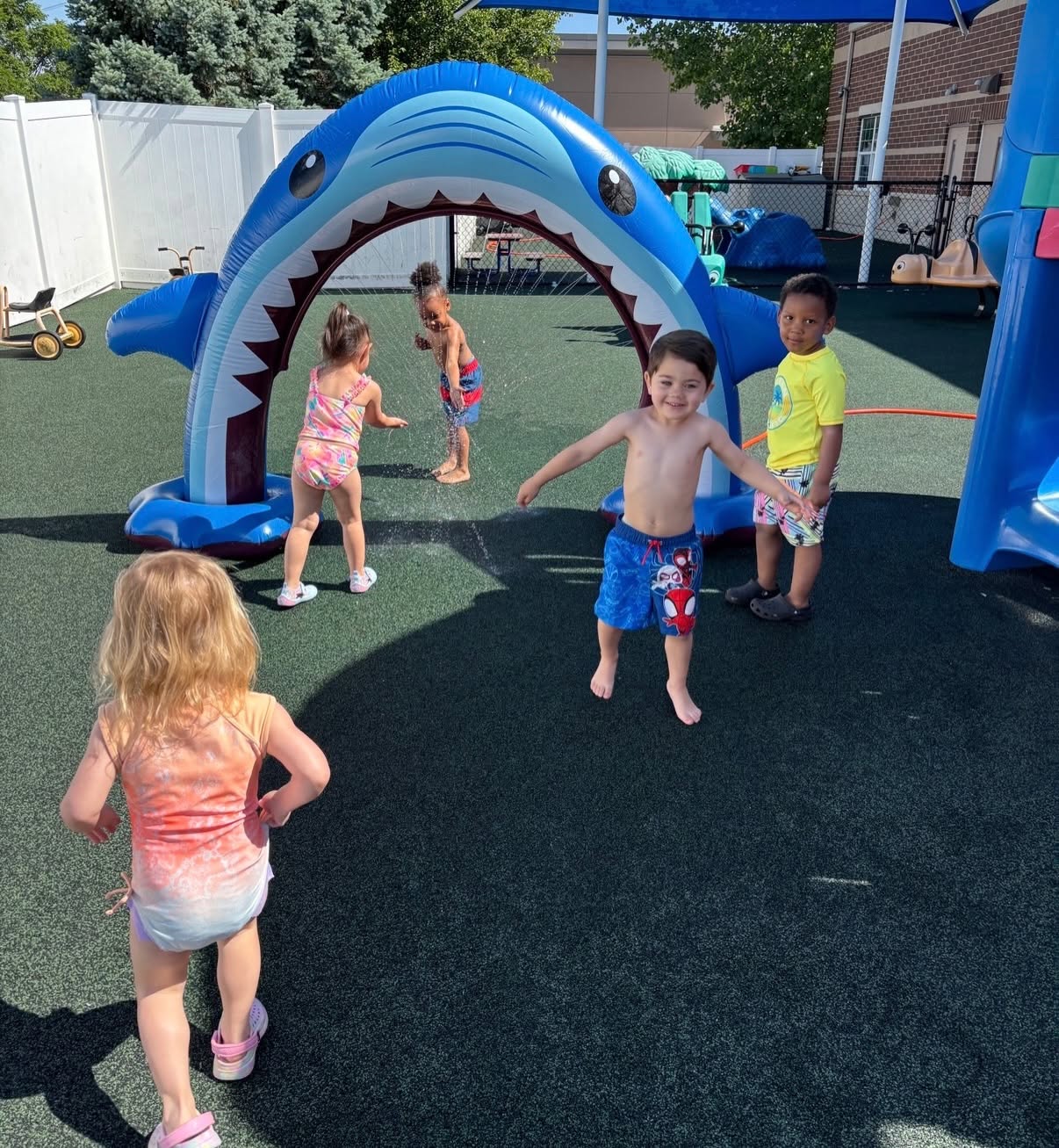 Children playing in a water sprinkler shaped like a shark