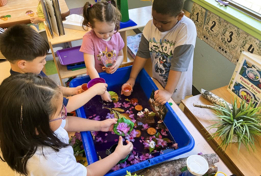 Children playing with flowers and water in a sensory tray