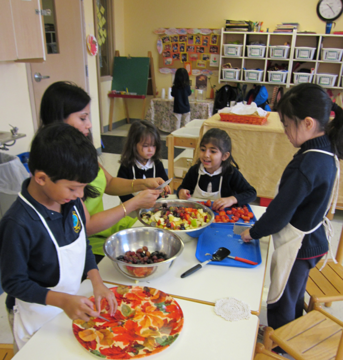 Adult and children preparing food in a classroom