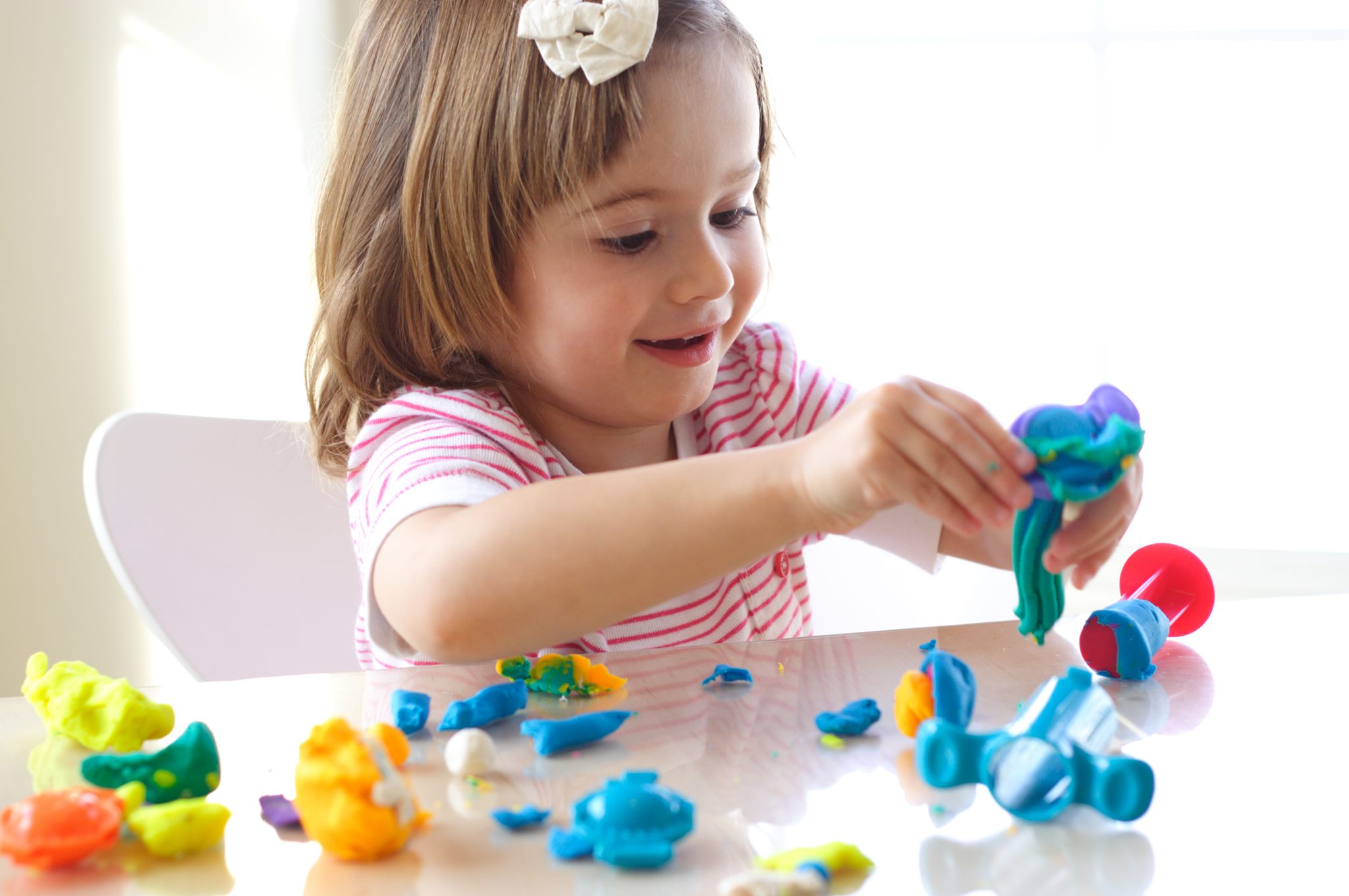 Child playing with colorful modeling clay at a table