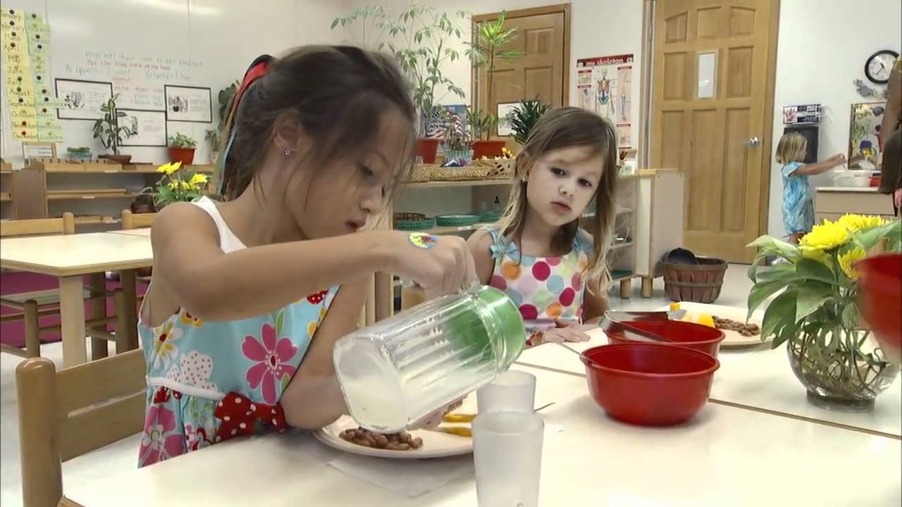 Child pouring from a container onto a plate, another child watching