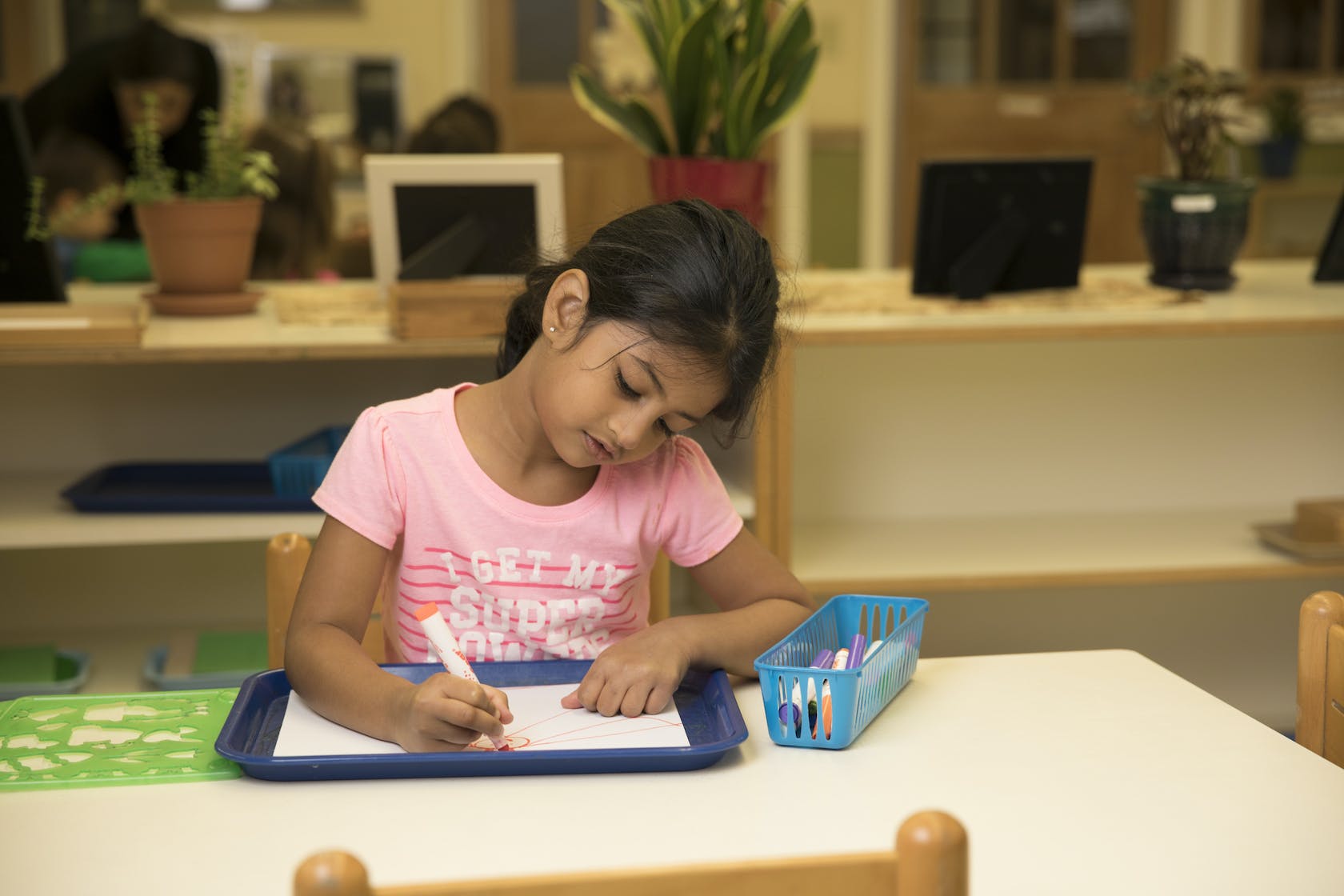 Child writing on paper at a table in a classroom