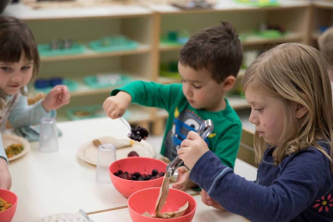 Children at a table serving themselves food from bowls