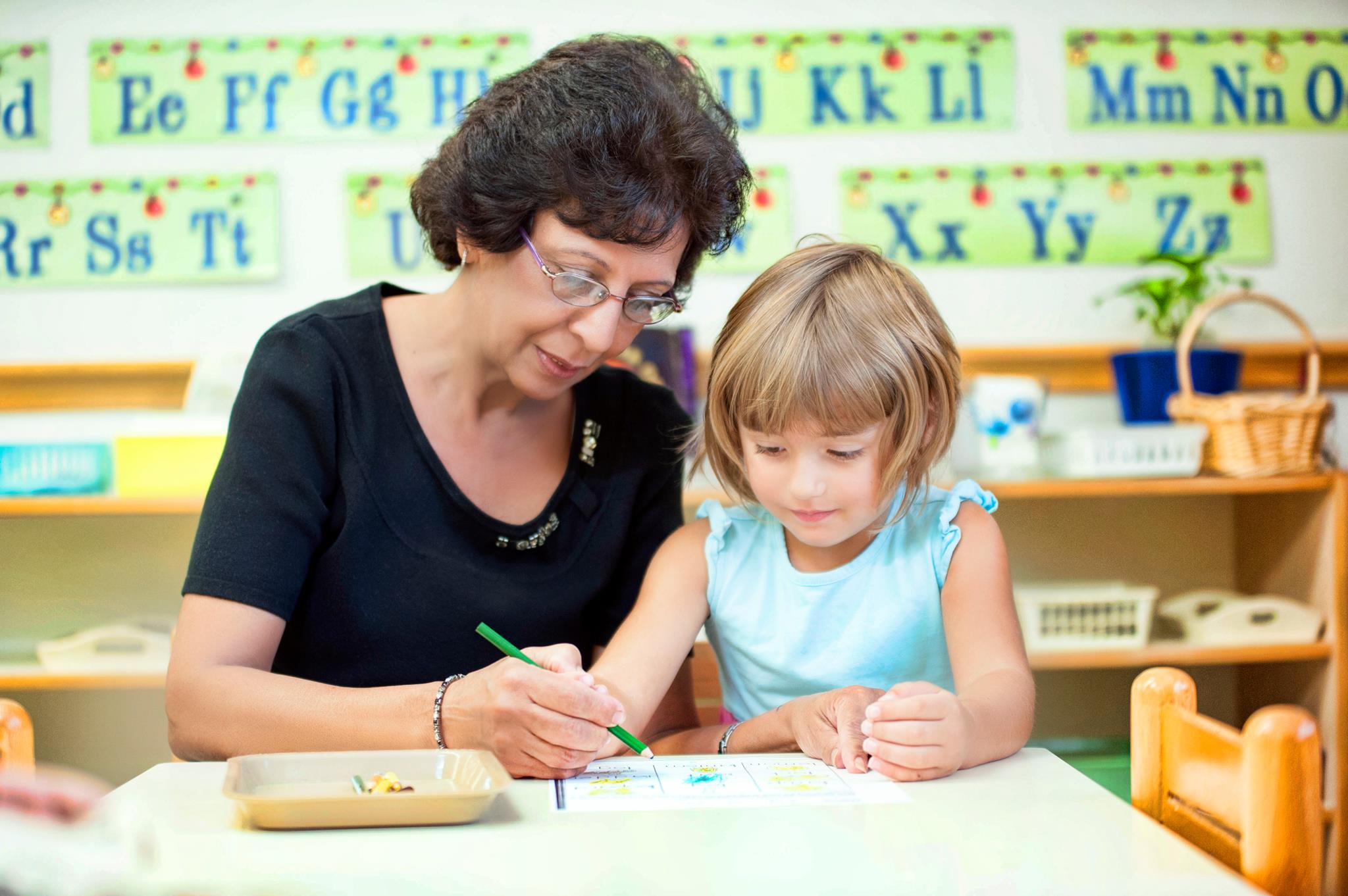 Adult and child drawing together in a classroom