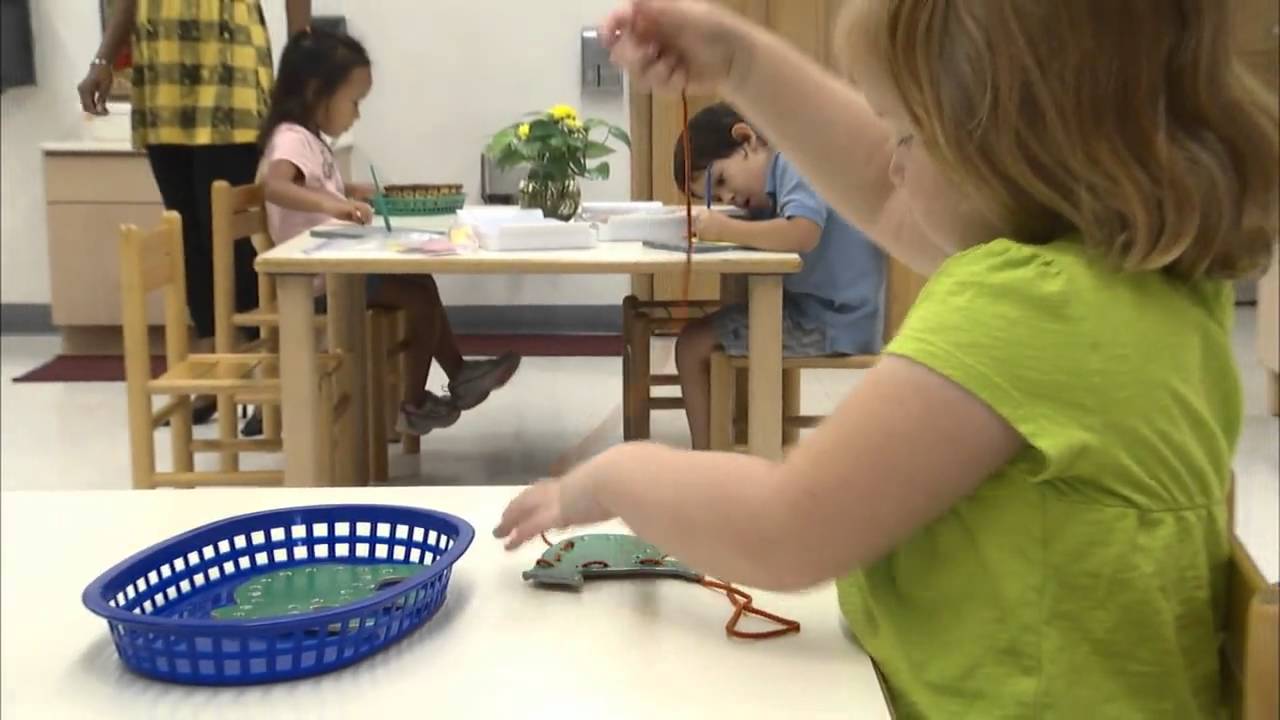 Child playing with a toy on a table in a classroom