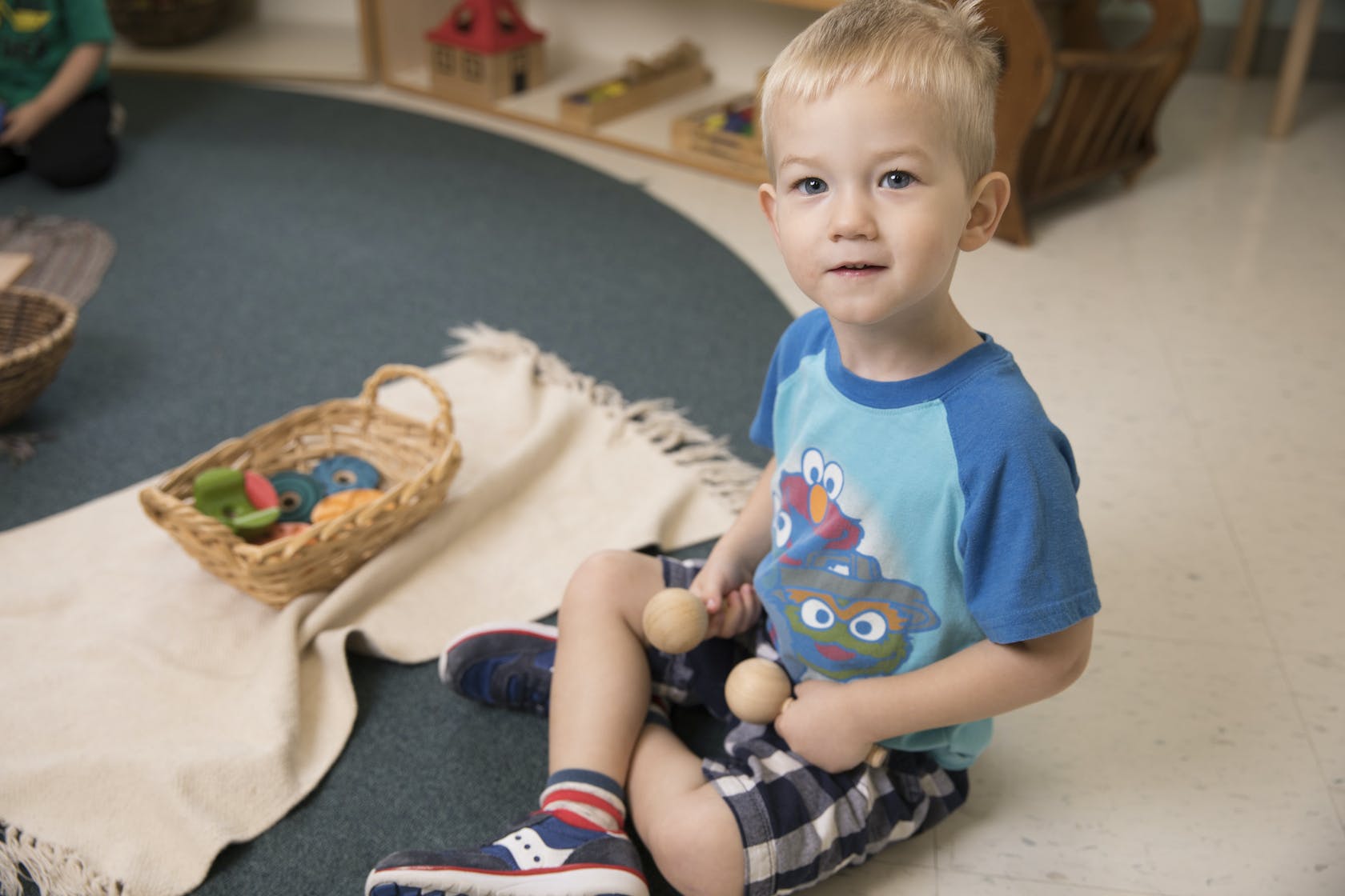 Child sitting on floor holding two wooden objects