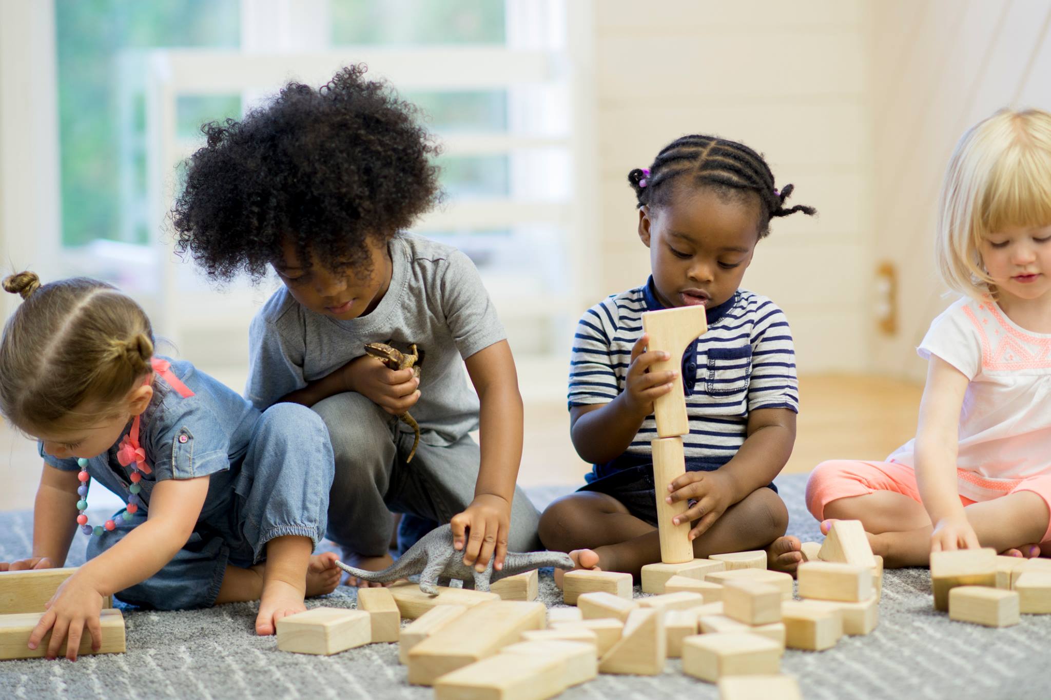 Four children playing with wooden blocks on the floor