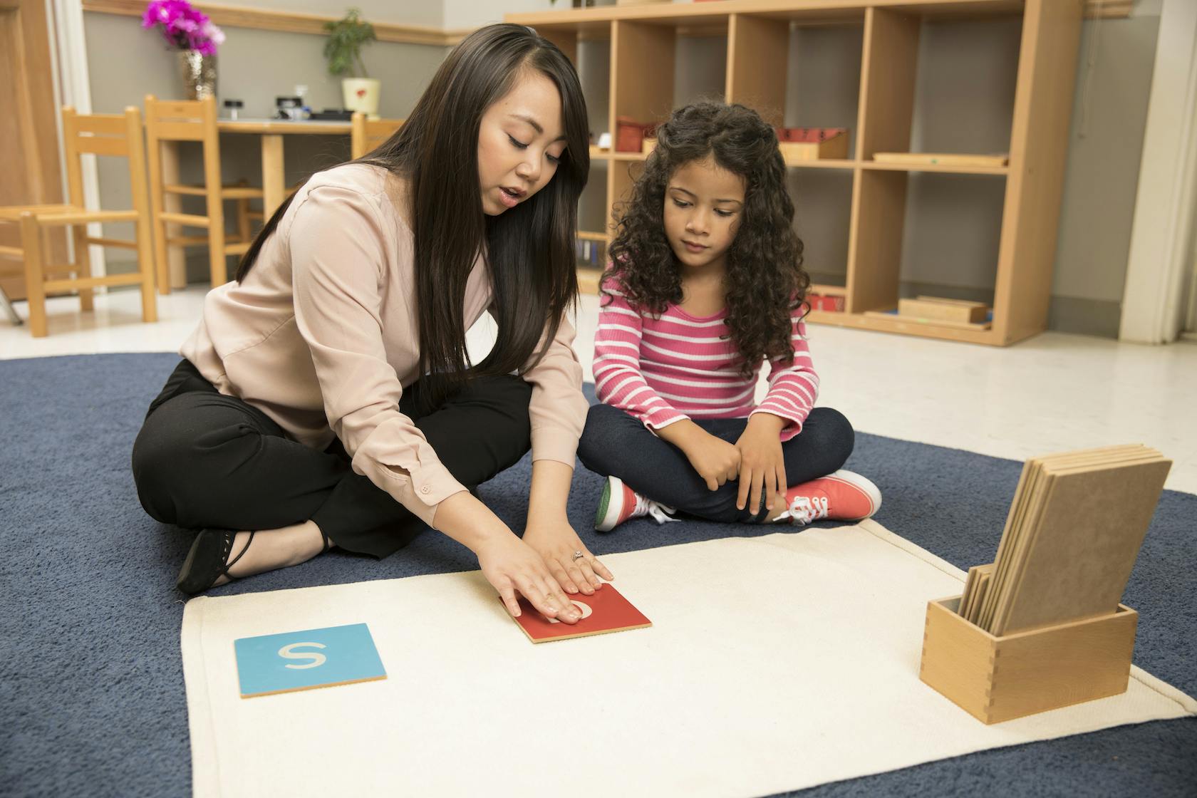 Adult and child on floor with learning materials