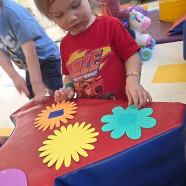 Child playing with flower cutouts on a soft play structure