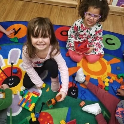 Two children playing with building blocks on a colorful rug