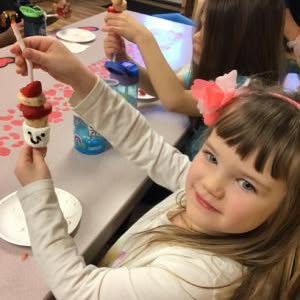 Child holding a skewer with fruit and marshmallows