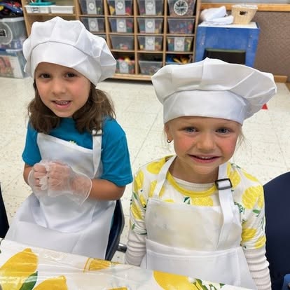 Two children wearing chef hats and aprons