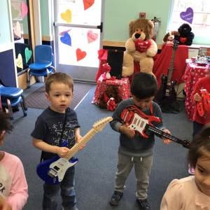 Two children holding toy guitars in a room