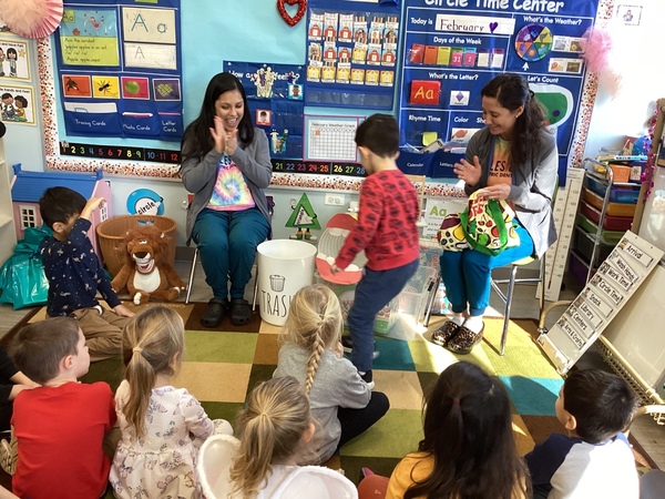 Two people leading a group of children in a classroom activity