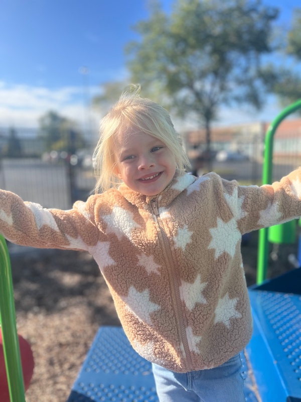 Child in a star-patterned jacket on a playground