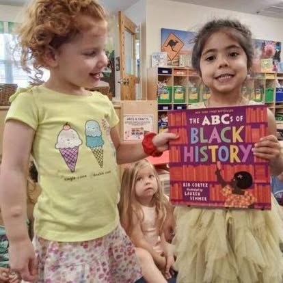 Child holding a book titled "The ABCs of Black History"