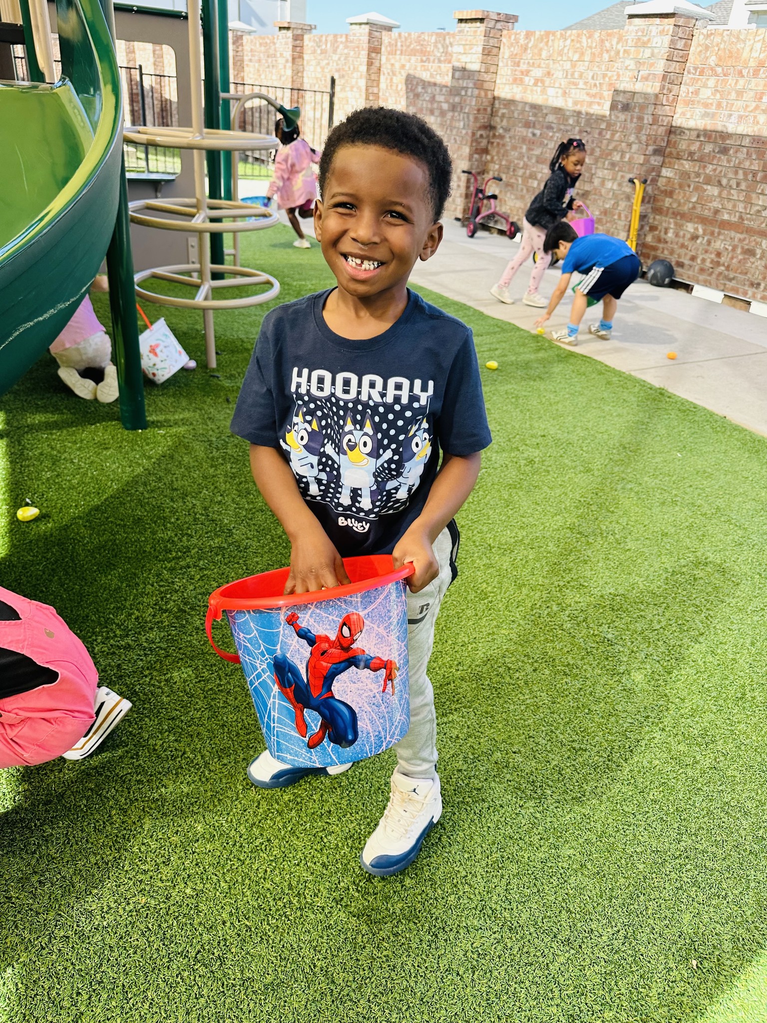 Child holding a Spider-Man bucket on a playground