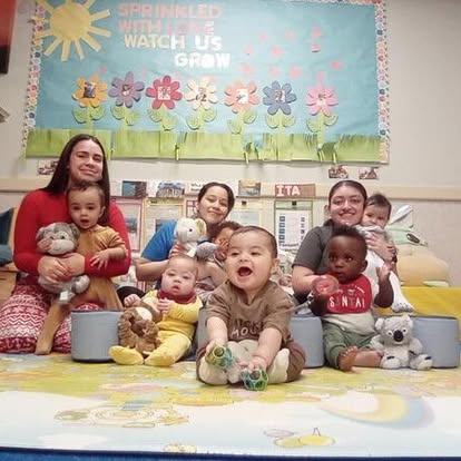 Three people with multiple babies in a classroom setting