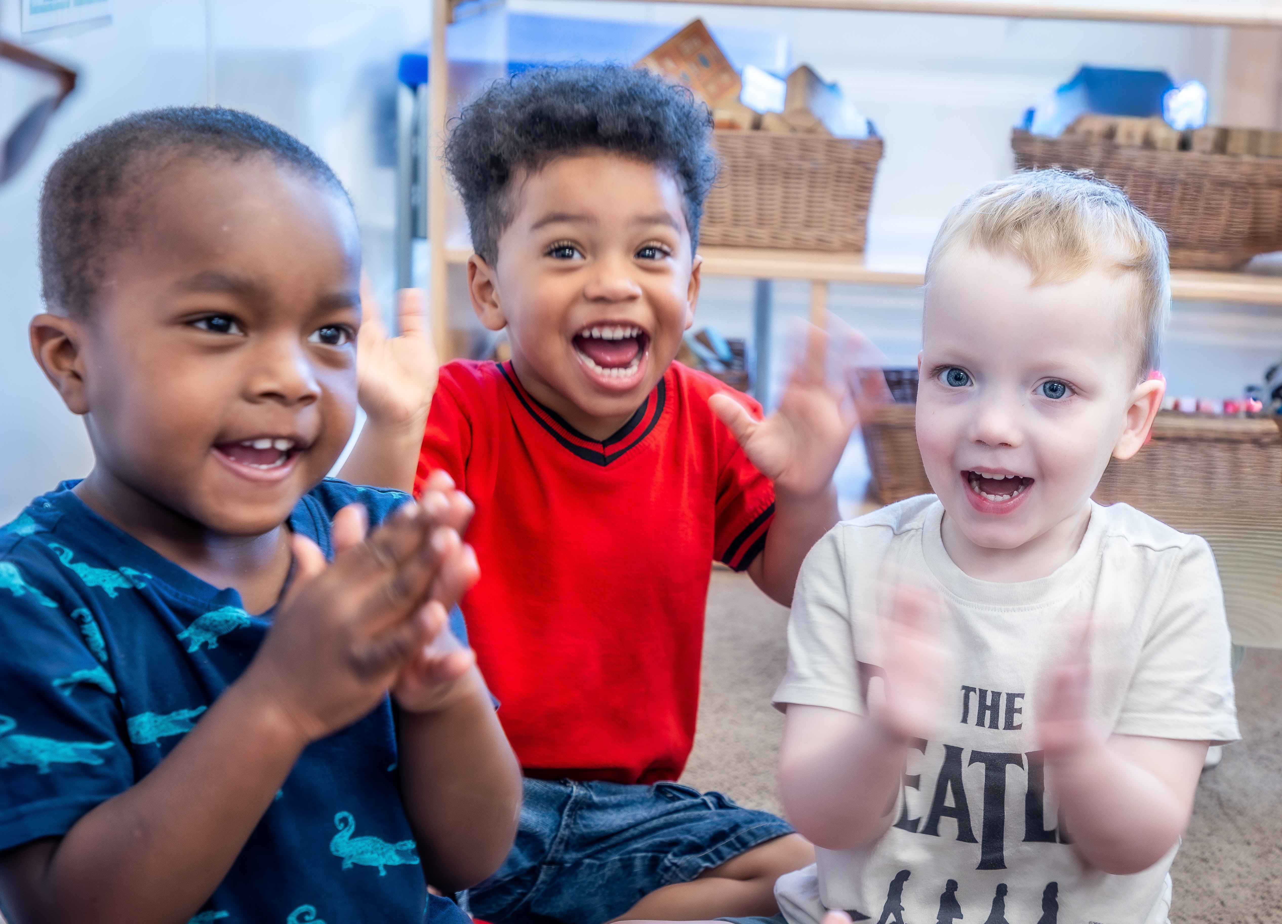Three children clapping in a classroom